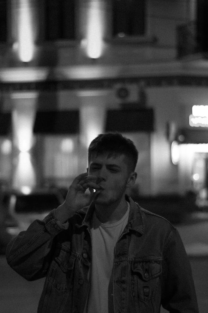 Black and white portrait of a man smoking outside at night in Romania.